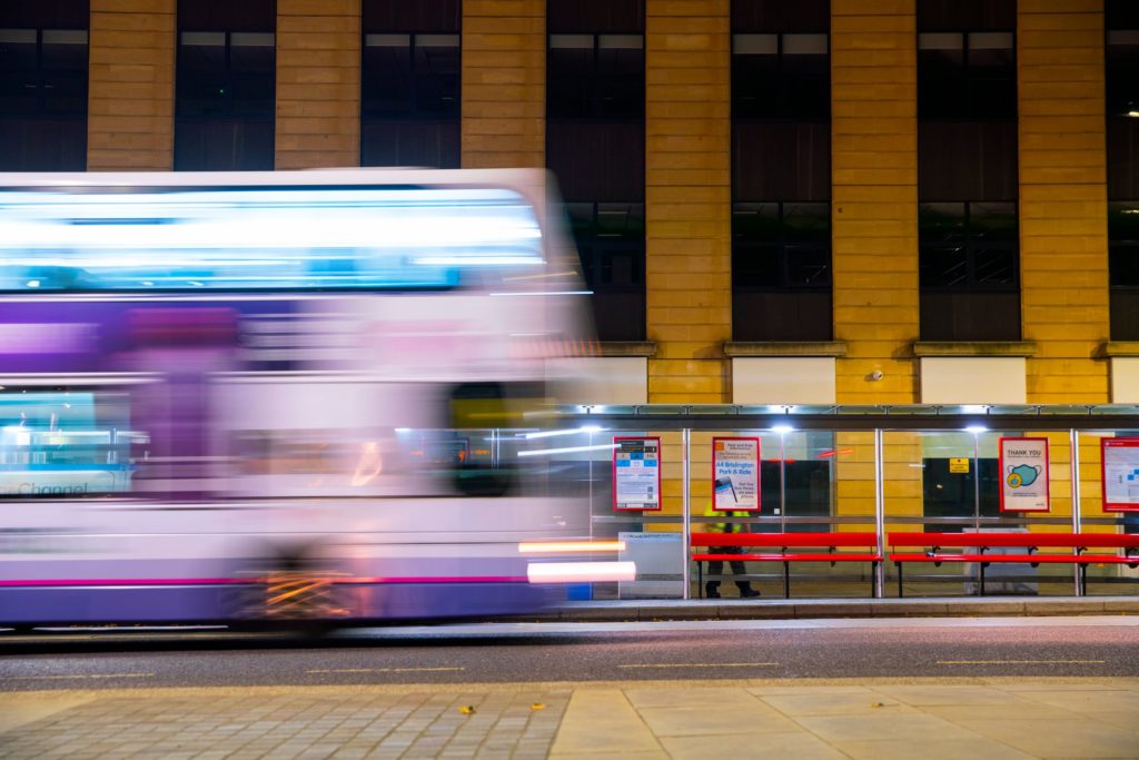 Bus passing a bus shelter at night time