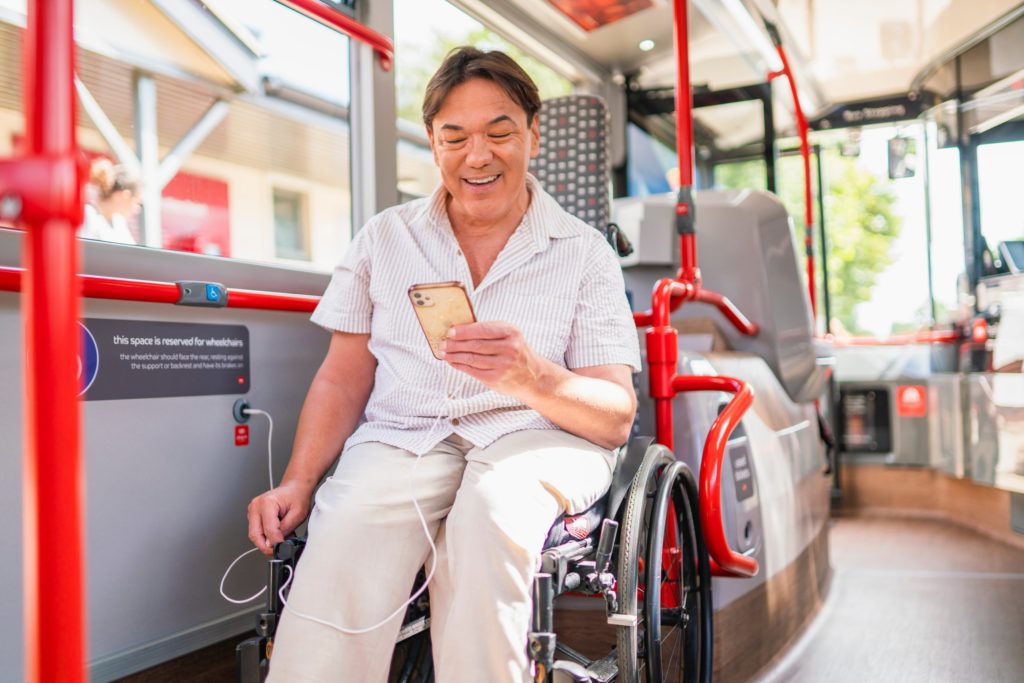Disabled person in wheelchair looking at their mobile phone on board a bus