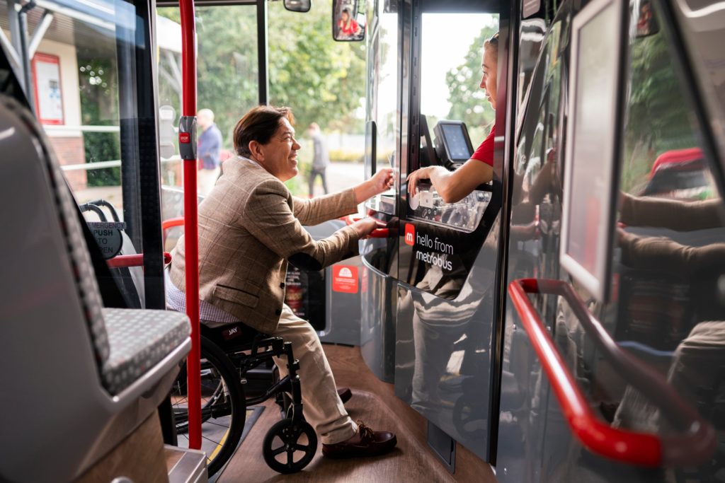 Disabled person in wheelchair scanning concessionary pass on metrobus