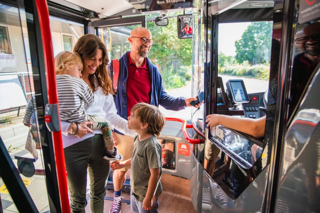 Family boarding a bus service and paying with a mobile phone
