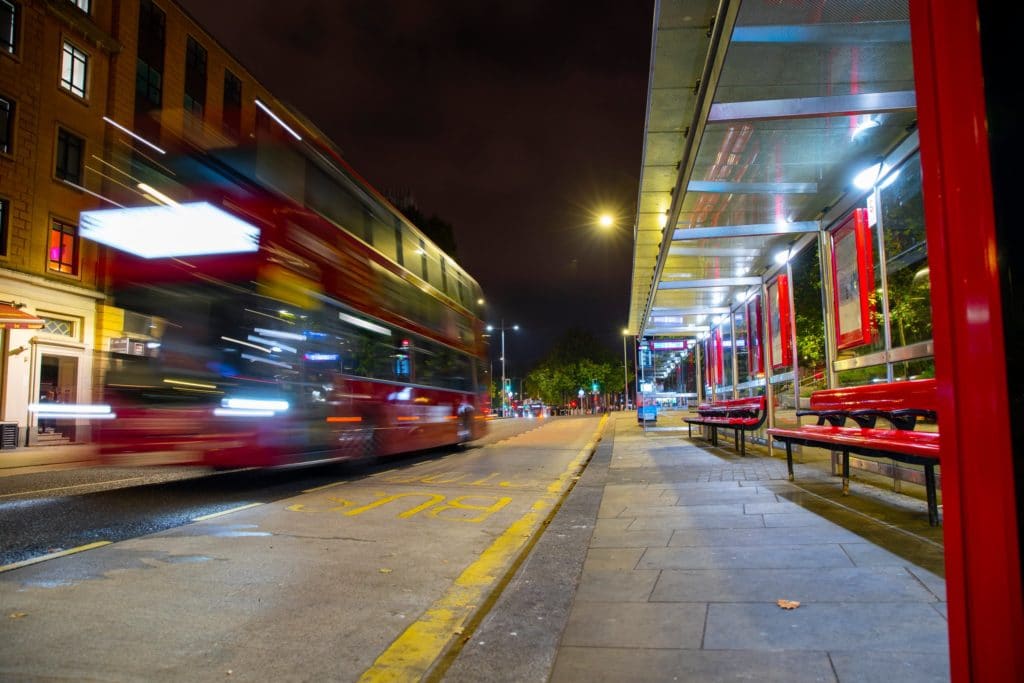 Bus shelter and moving bus at night time.