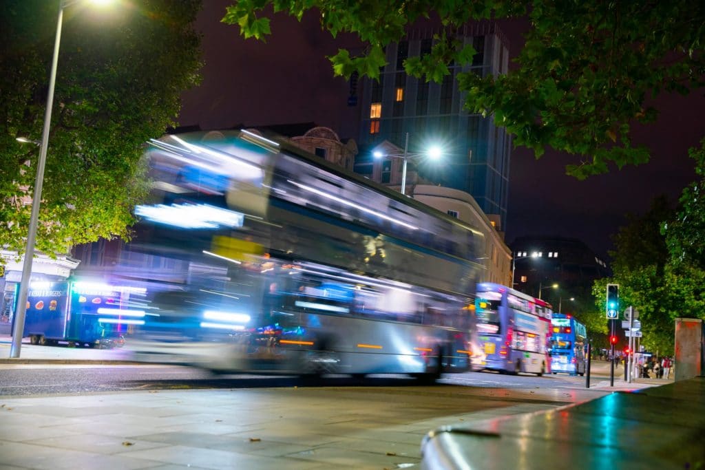 Several buses moving in city centre at night time.