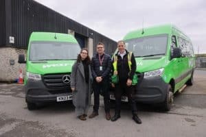 Clara Can, Steve Hogg and Jonathan Hampson standing in front of two green WESTlink minibuses.