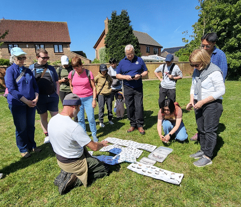 Photo of the walk leader crouching down and arranging posters of local wildlife to show attendees.