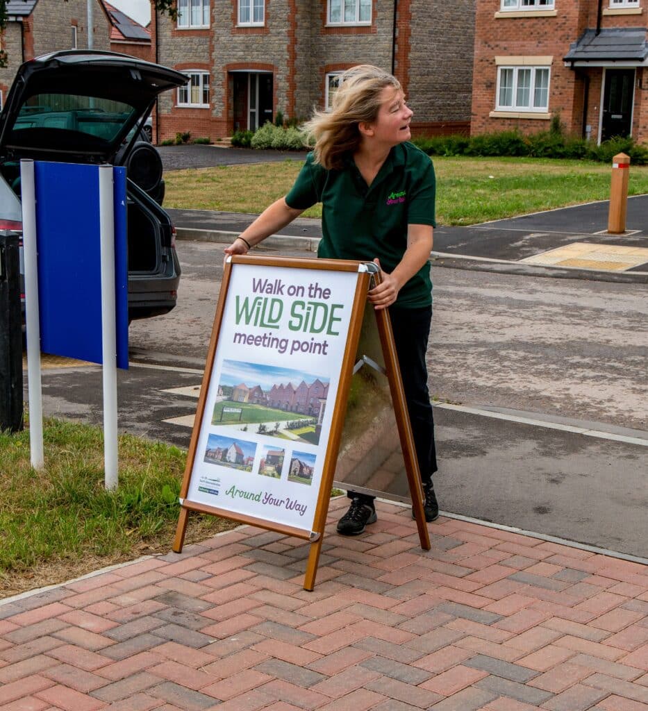 Photo of a travel planning officer setting up a promotional A-board sign to show the meeting point for the Walk on the Wild Side event.