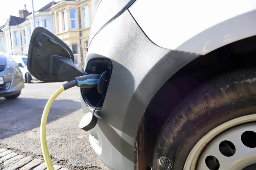 EV cabled plugged into a car on a residential street.
