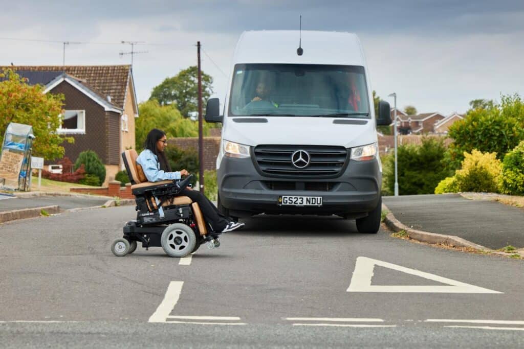 residential road juction with a truck stopped to allow a wheelchair user to cross the road.