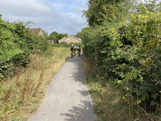 Nailsea golden valley cycle path within a residential area with 3 cyclists along it.