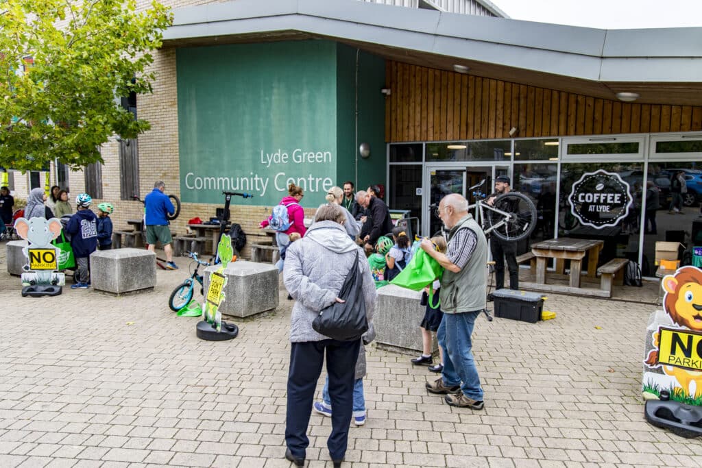 Photo of the sustainable travel roadshow event outside the Lyde Green Community Centre showing the various stalls, Dr Bike, and visitors.
